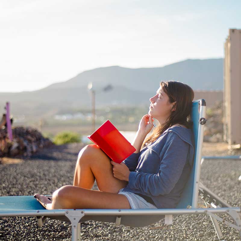 woman sitting on a roof top journaling in a chair